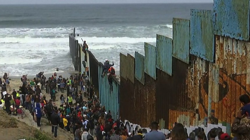 immigrants-climbing-over-border-wall
